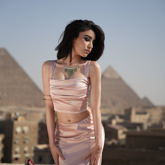 Woman in a pink dress standing on a rooftop with cityscape in the background